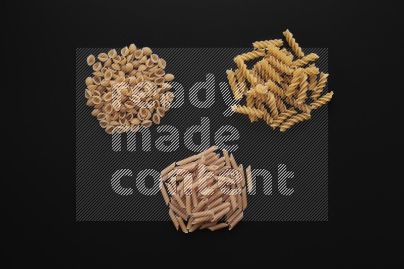 Different pasta types in bunches on black background