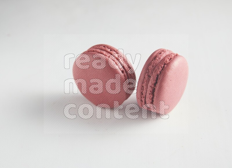 45º Shot of two Pink Raspberry macarons on white background