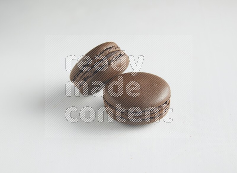 45º Shot of two Brown Dark Chocolate macarons on white background