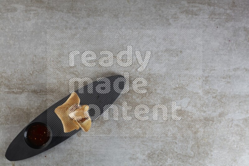 wonton cups with soy sauce ramkin on oval slate on grey textured counter top