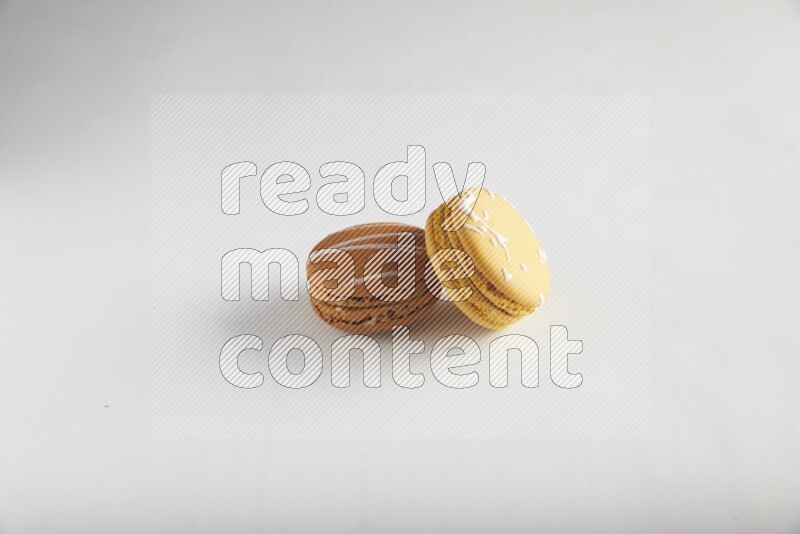 45º Shot of of two assorted Brown Irish Cream, and Yellow Piña Colada macarons on white background