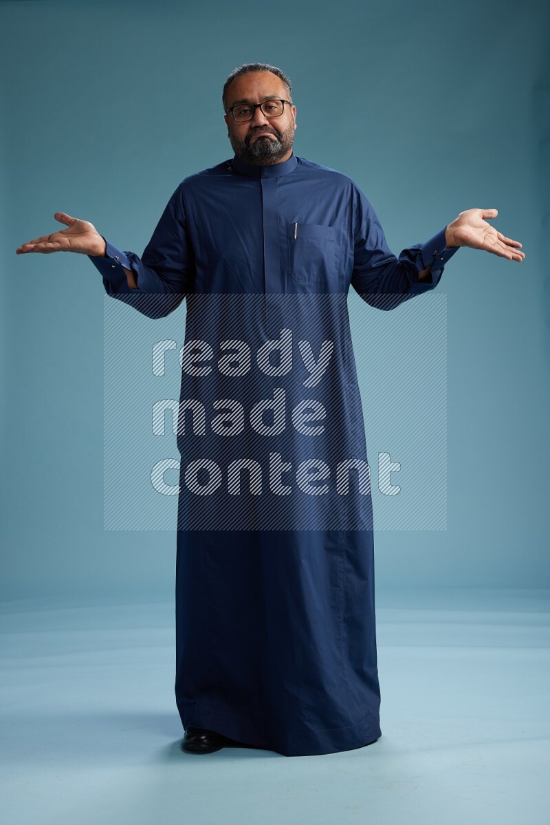 Saudi Man without shimag Standing Interacting with the camera on blue background