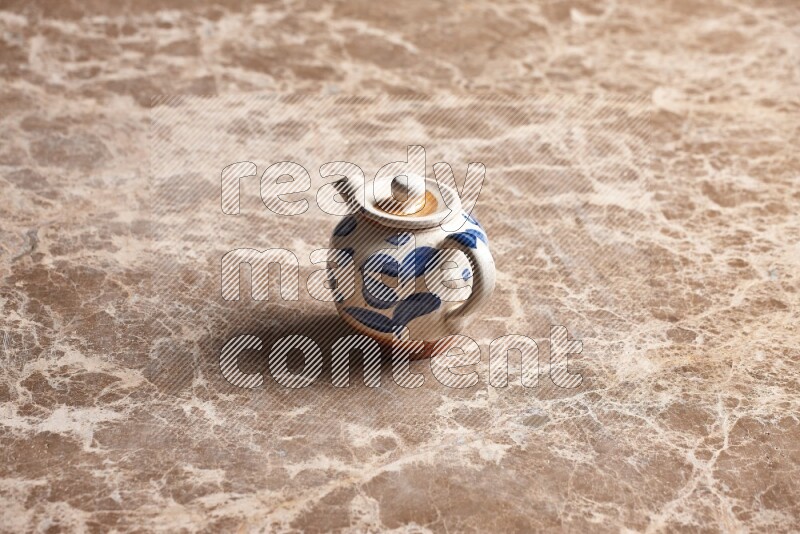 A pottery teapot on beige marble background