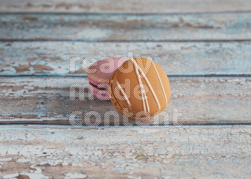 45º Shot of of two assorted Brown Irish Cream, and Purple Strawberry macarons  on light blue background