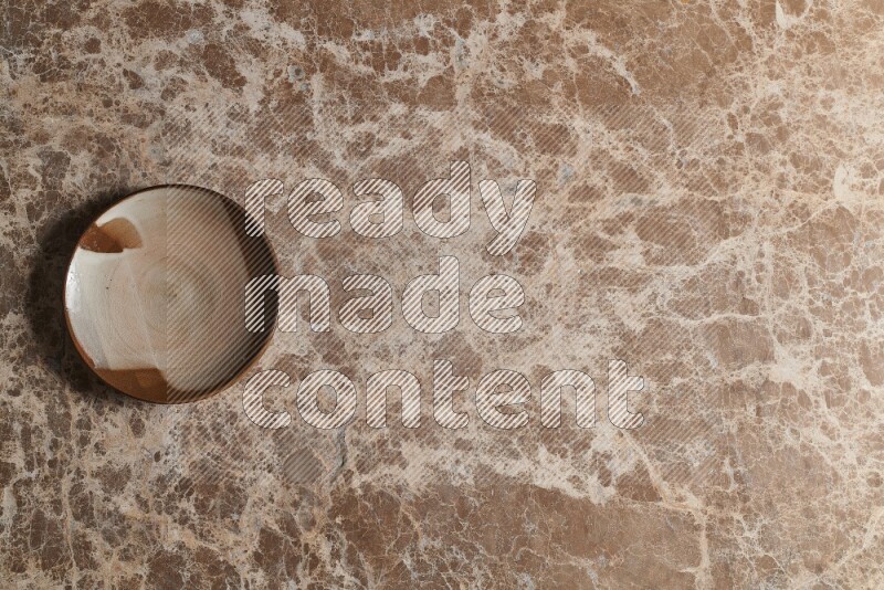 A decorative pottery plate on beige marble background