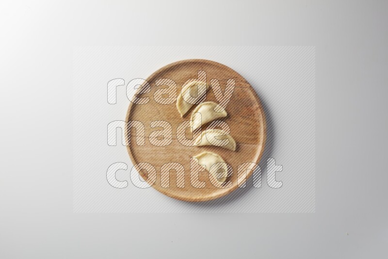 Four Sambosas on a wooden round plate on a white background