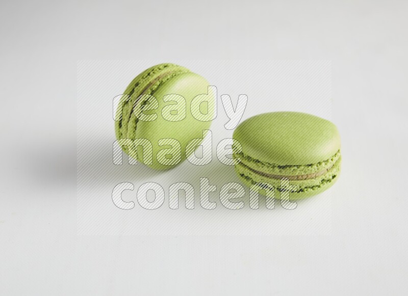 45º Shot of two Green Pistachio macarons on white background