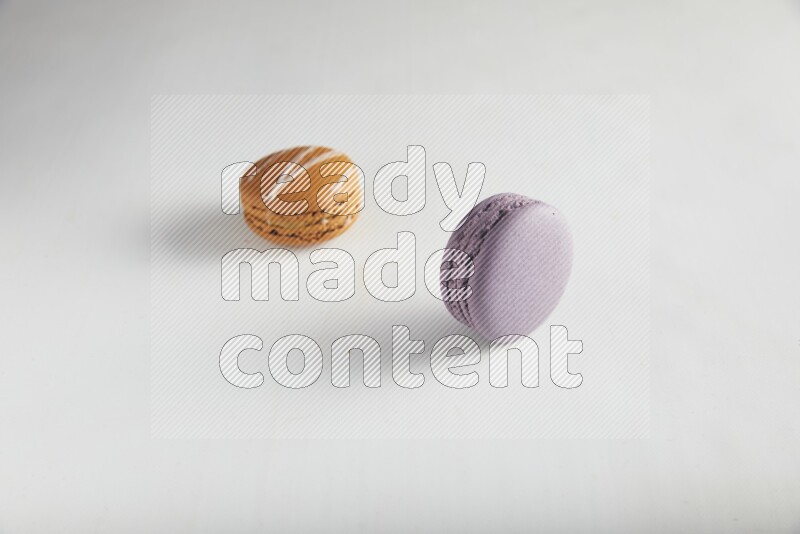 45º Shot of of two assorted Brown Irish Cream, and Purple Blueberry macarons on white background