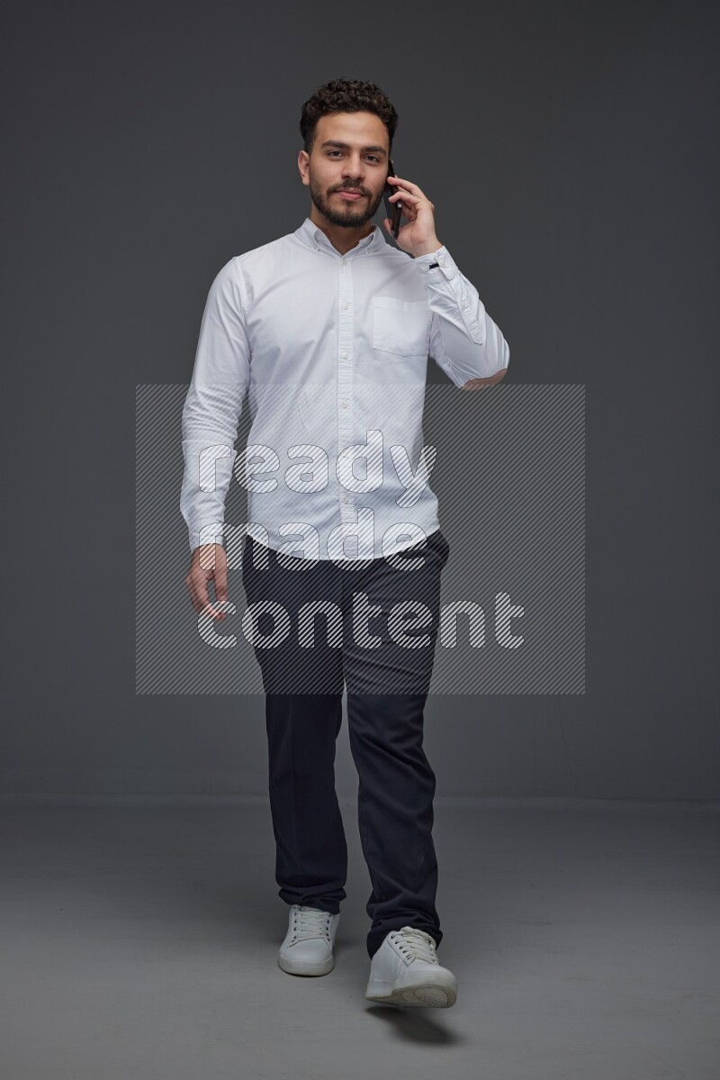 A man wearing smart casual talking in the phone eye level on a gray background
