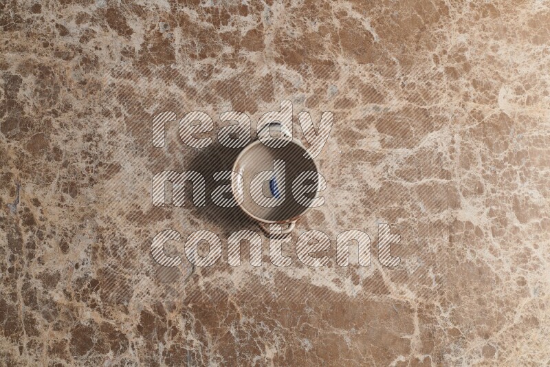 A multicolored pottery bowl on beige marble background