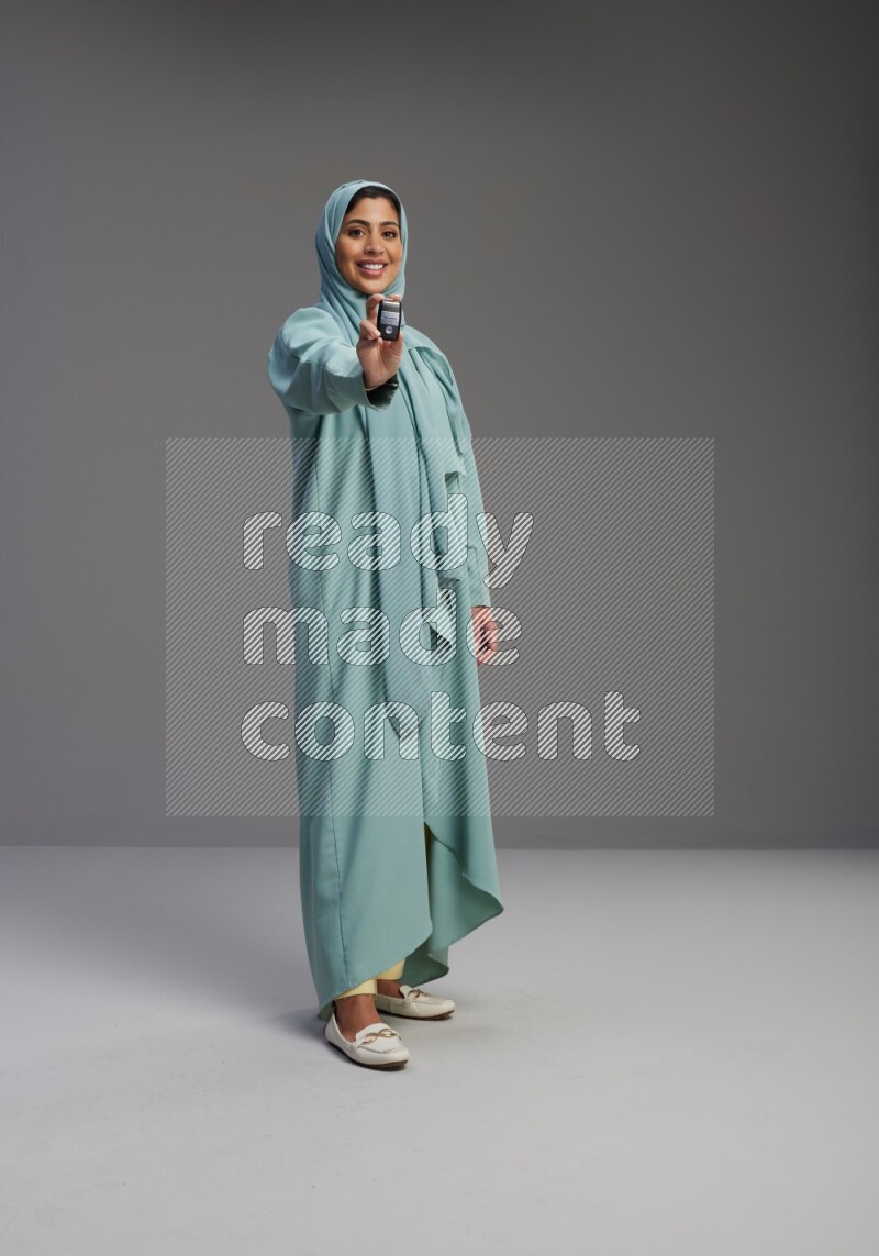 Saudi Woman wearing Abaya standing holding car key on Gray background