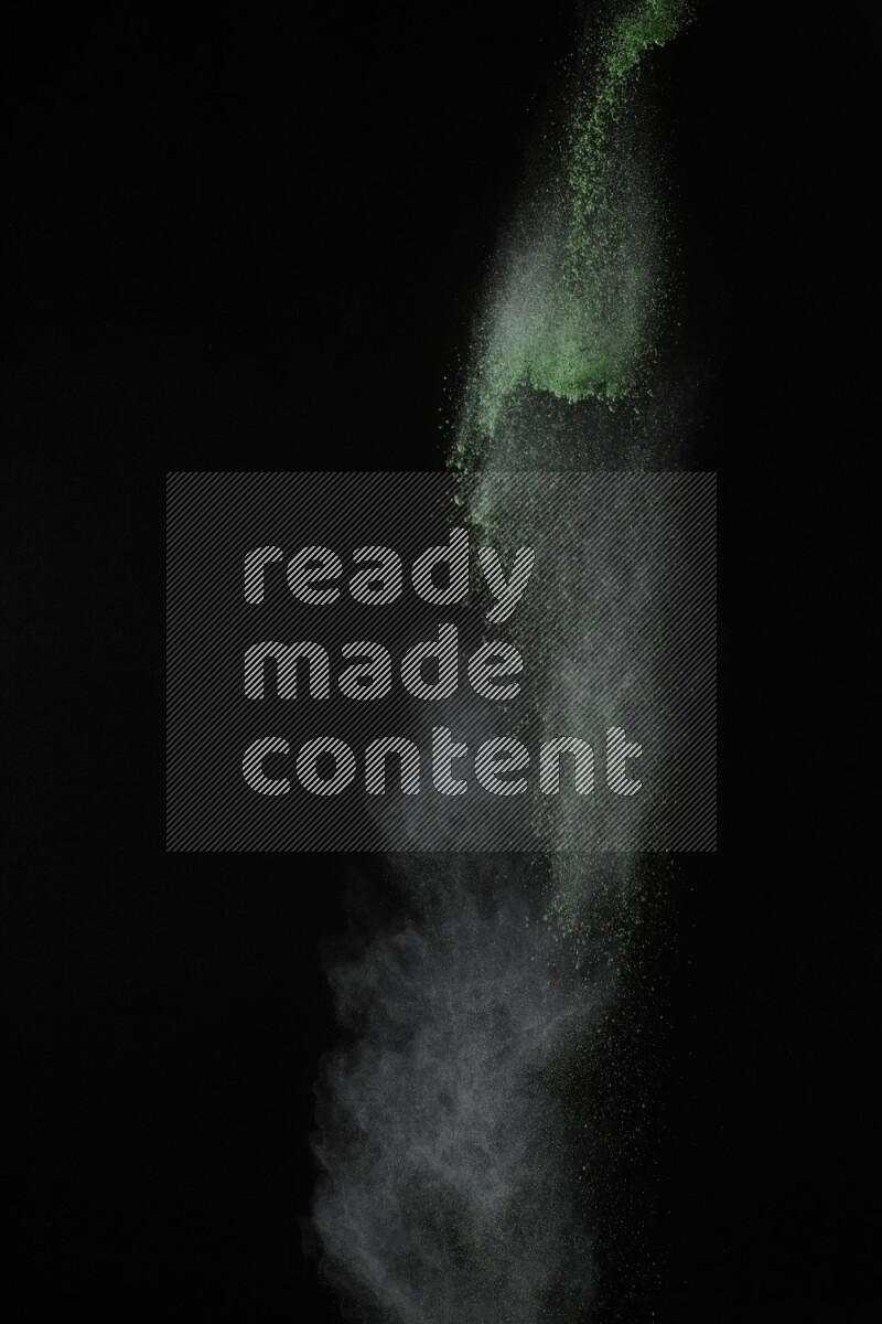 A side view of green powder explosion on black background