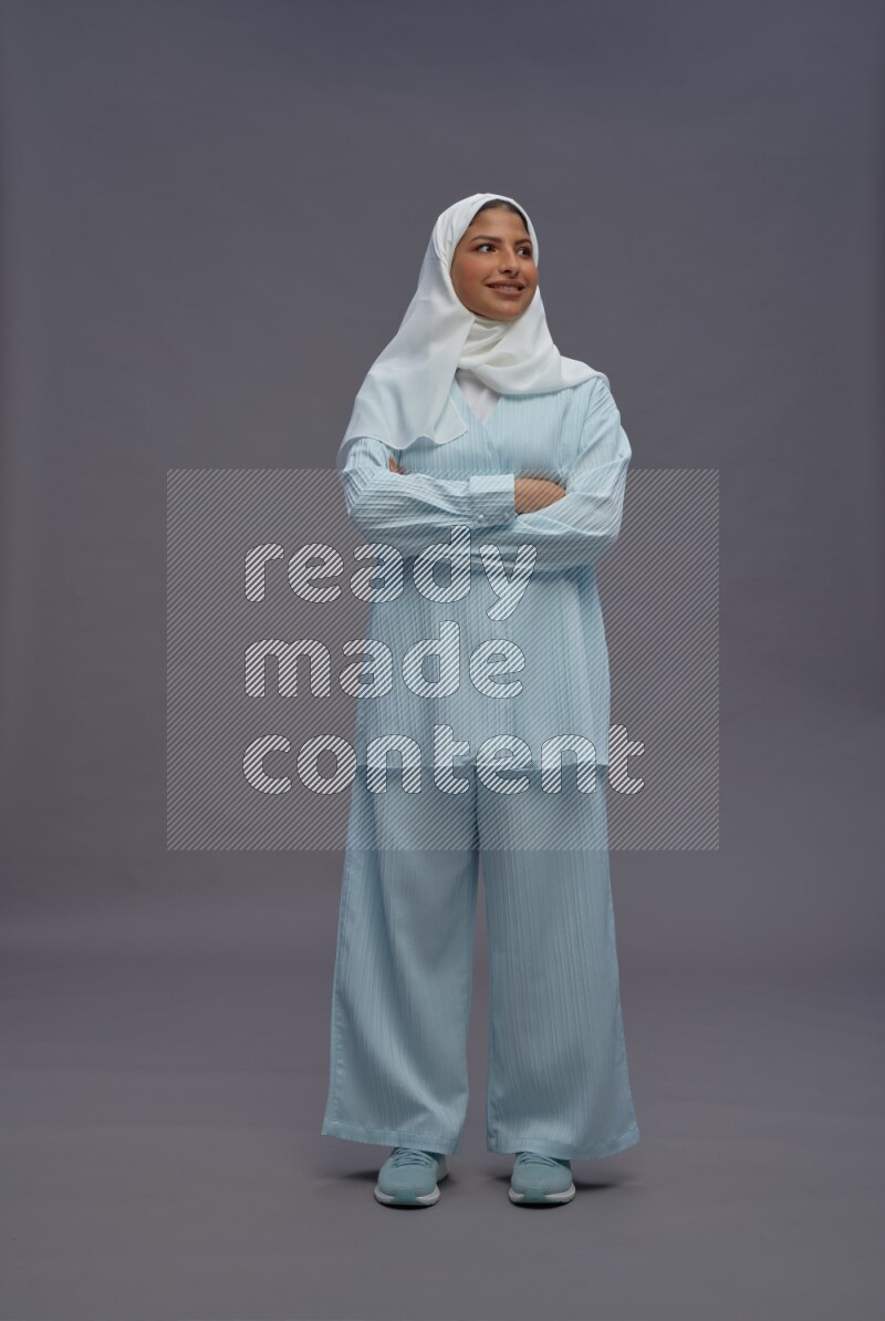Saudi woman wearing hijab clothes standing with crossed arms on gray background