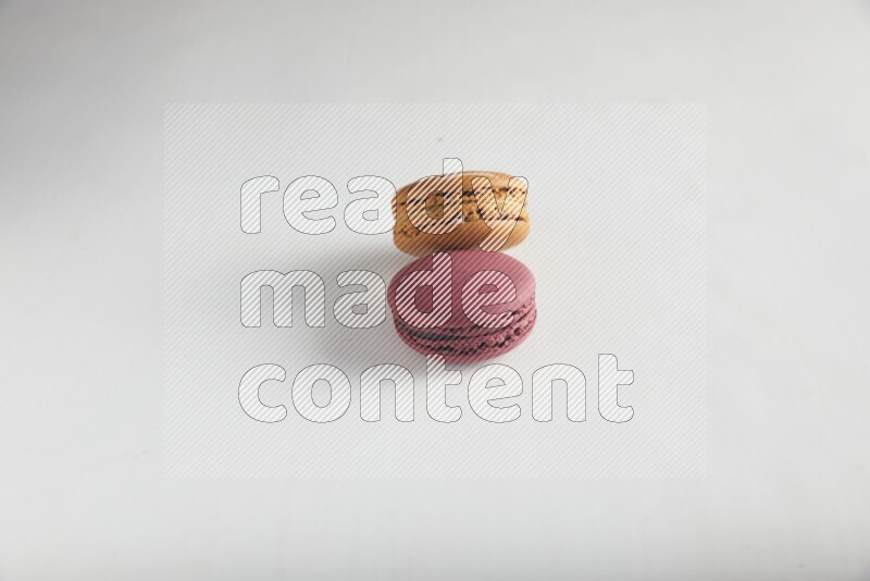 45º Shot of of two assorted Brown Irish Cream, and Red Cherry macarons on white background