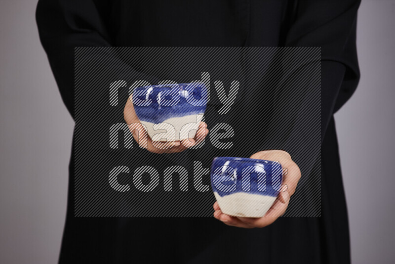A woman in black abaya holding different pottery essentials in different positions