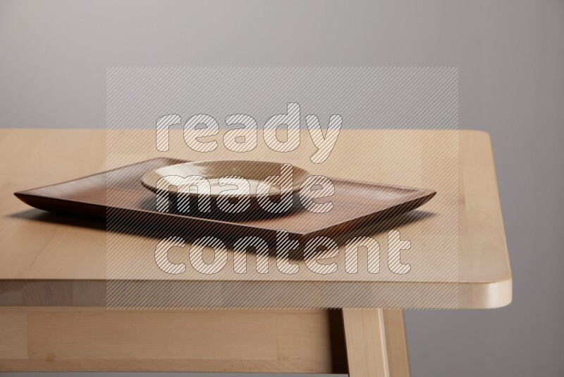 multicolored plate on a rectangular wooden tray on the edge of wooden table