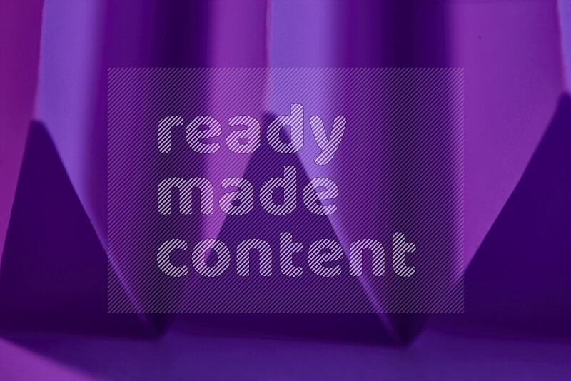 A close-up abstract image showing sharp geometric paper folds in purple gradients