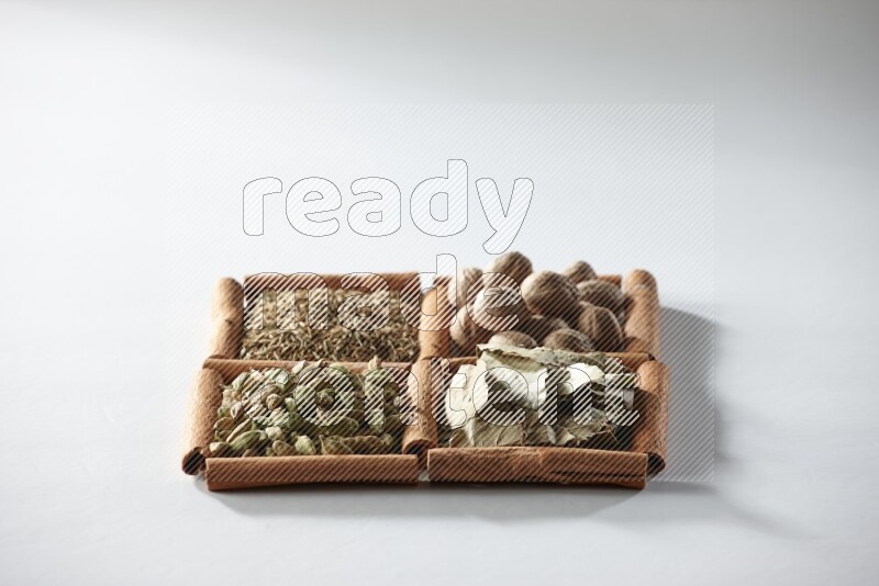 4 squares of cinnamon sticks full of nutmegs, bay laurel leaves, cardamom and cumin on white flooring