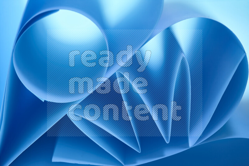 An artistic display of paper folds creating a harmonious blend of geometric shapes, highlighted by soft lighting in blue tones