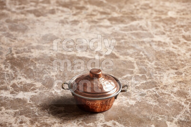 A small copper pot on beige marble background