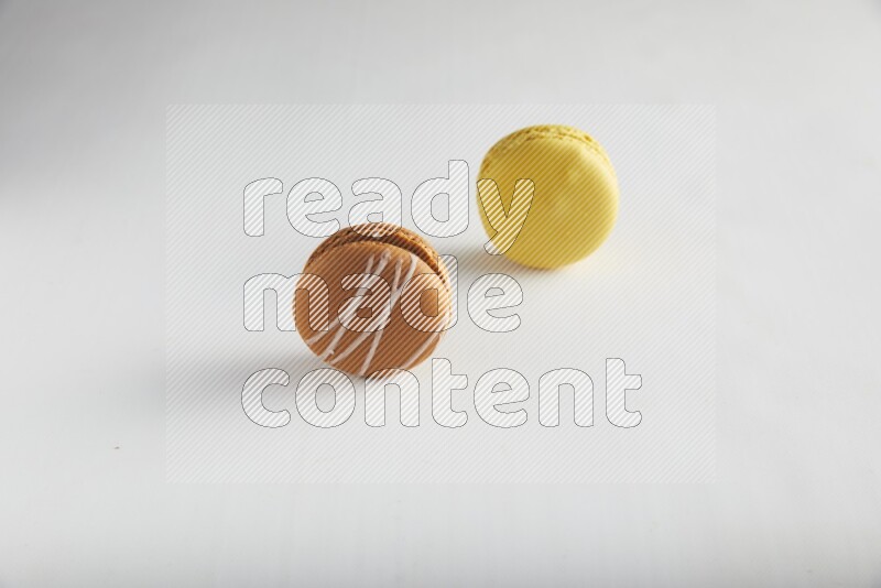 45º Shot of of two assorted Brown Irish Cream, and Yellow Lemon macarons on white background