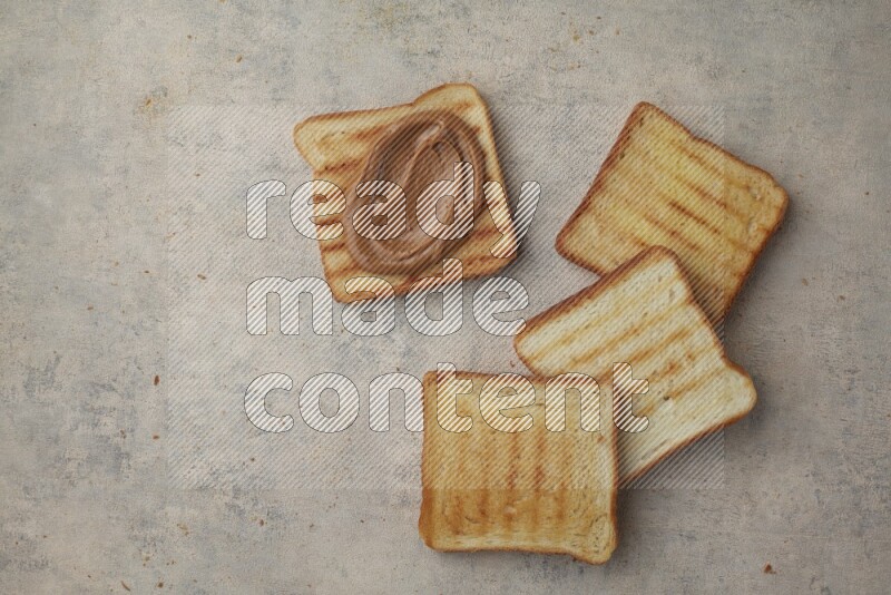 Creamy peanut butter on a toasted white toast and toasted white toast slices on a light blue textured background
