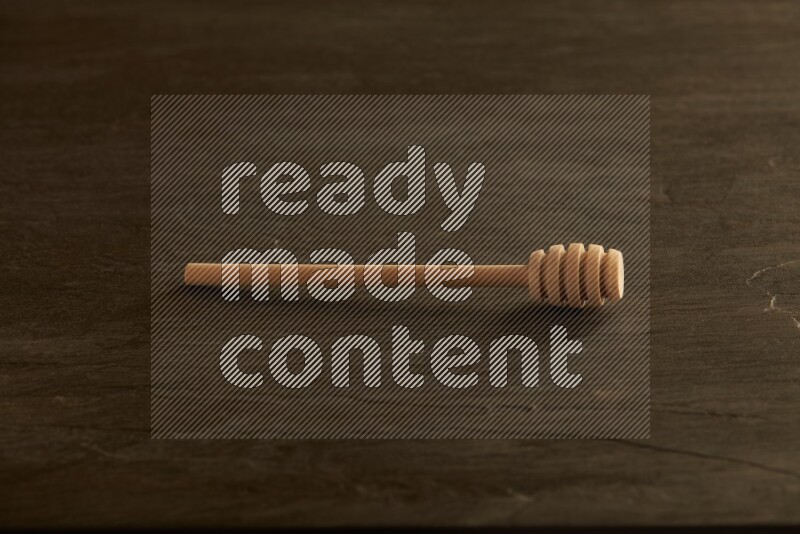 Wooden honey dipper on black slate background