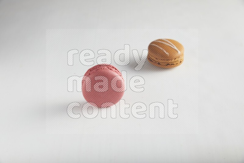 45º Shot of of two assorted Brown Irish Cream, and Pink Raspberry macarons on white background