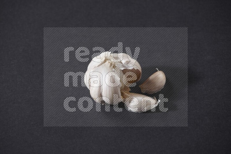 A whole garlic bulb placed on a black flooring