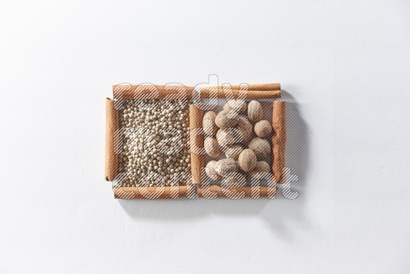 2 squares of cinnamon sticks full of white pepper and nutmegs on white flooring