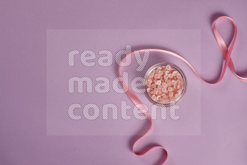 A pink and purple collection of sewing and tailoring tools arranged on a purple background