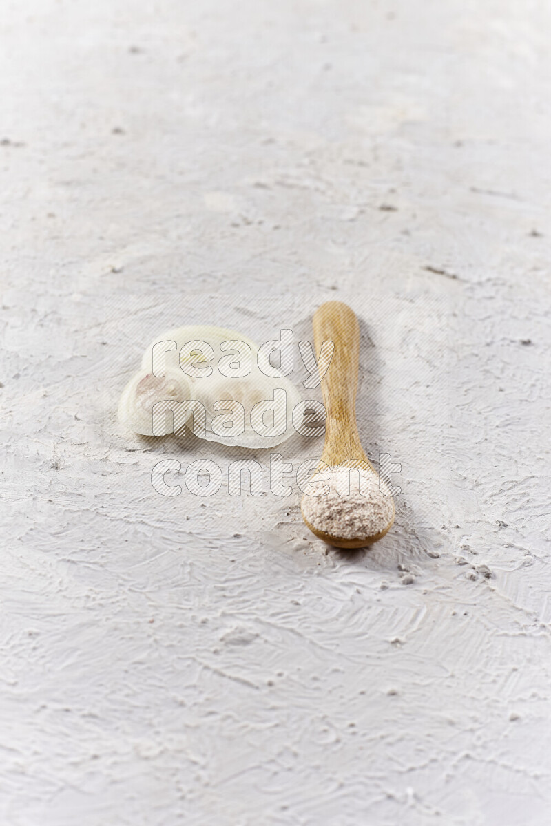 A wooden spoon full of onion powder on white background