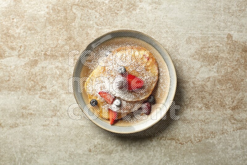 Three stacked mixed berries pancakes in a bicolor plate on beige background