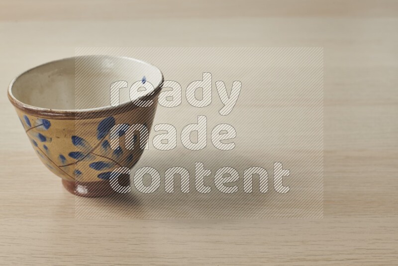 A decorative pottery bowl on light wooden background