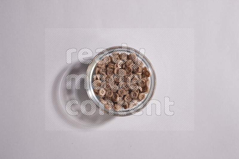 Colored buttons in a glass bowl on grey background