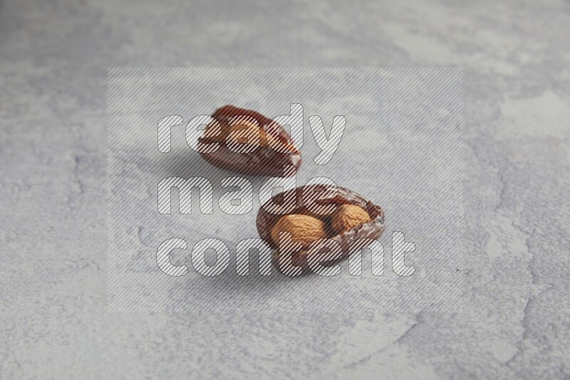 Two Almond stuffed date on a light grey background