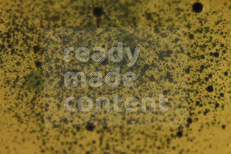 Close-ups of abstract green watercolor drops on oil Surface on yellow background