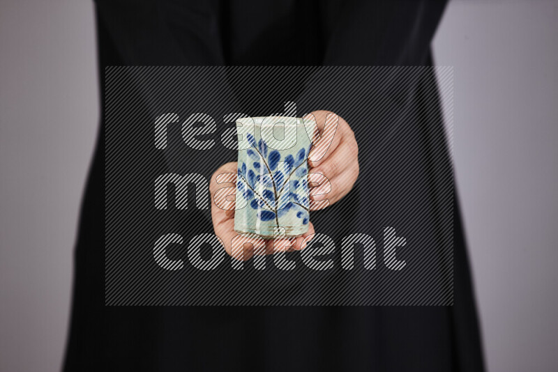 A woman in black abaya holding different pottery essentials in different positions