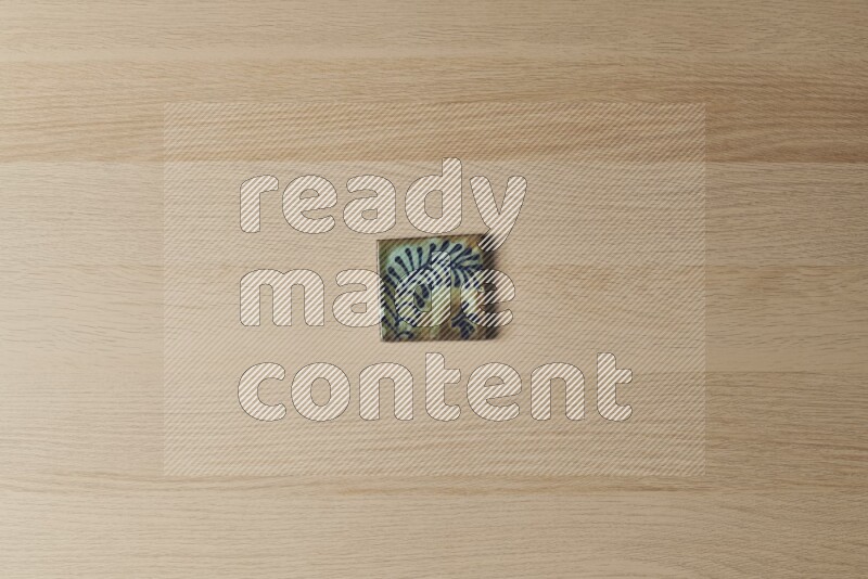 A decorative pottery coaster on light wooden background
