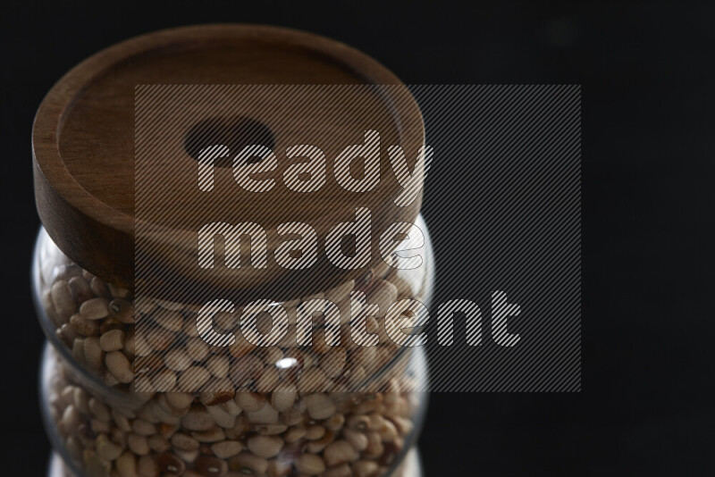 Black-eyed peas in a glass jar on black background