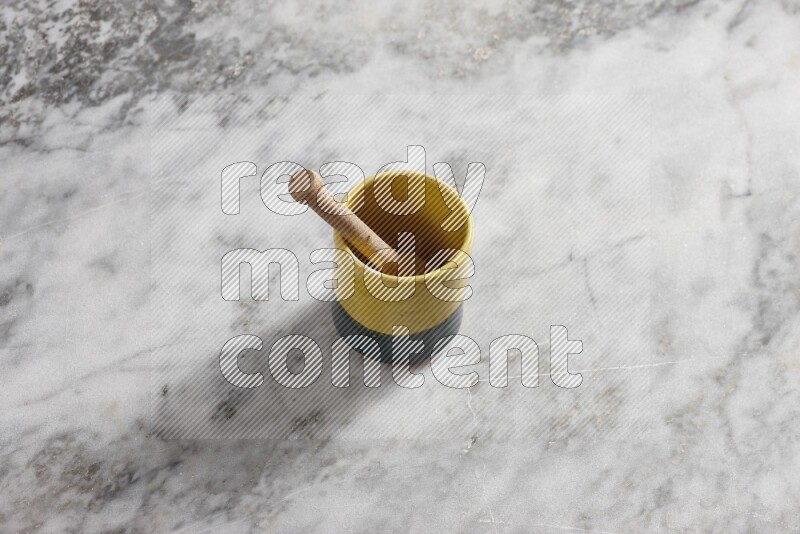 Multicolored pottery cup with wooden honey dipper in it on grey marble background