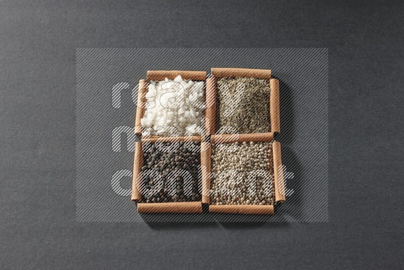 4 squares of cinnamon sticks full of black pepper, cumin, white pepper and white salt on black flooring