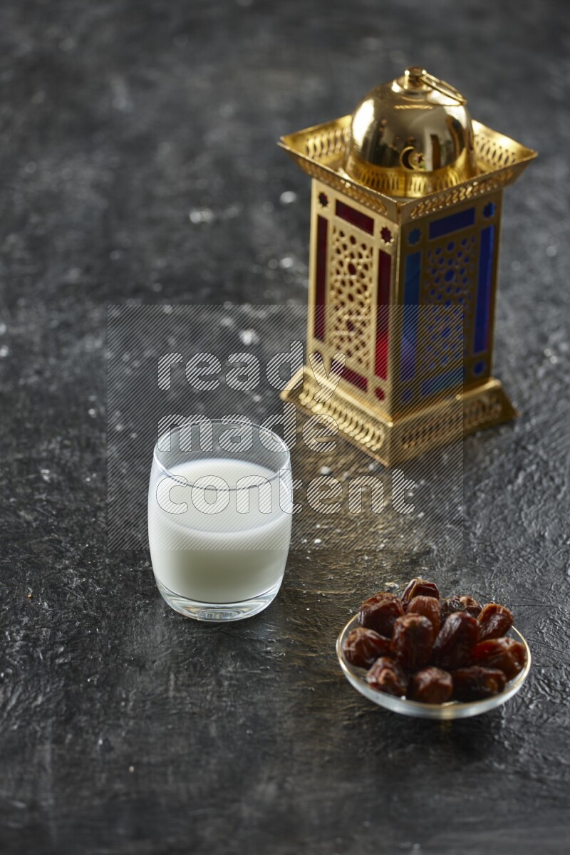 A golden lantern with different drinks, dates, nuts, prayer beads and quran on textured black background
