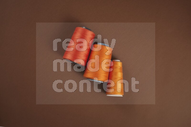 An orange collection of sewing and tailoring tools arranged on a brown background