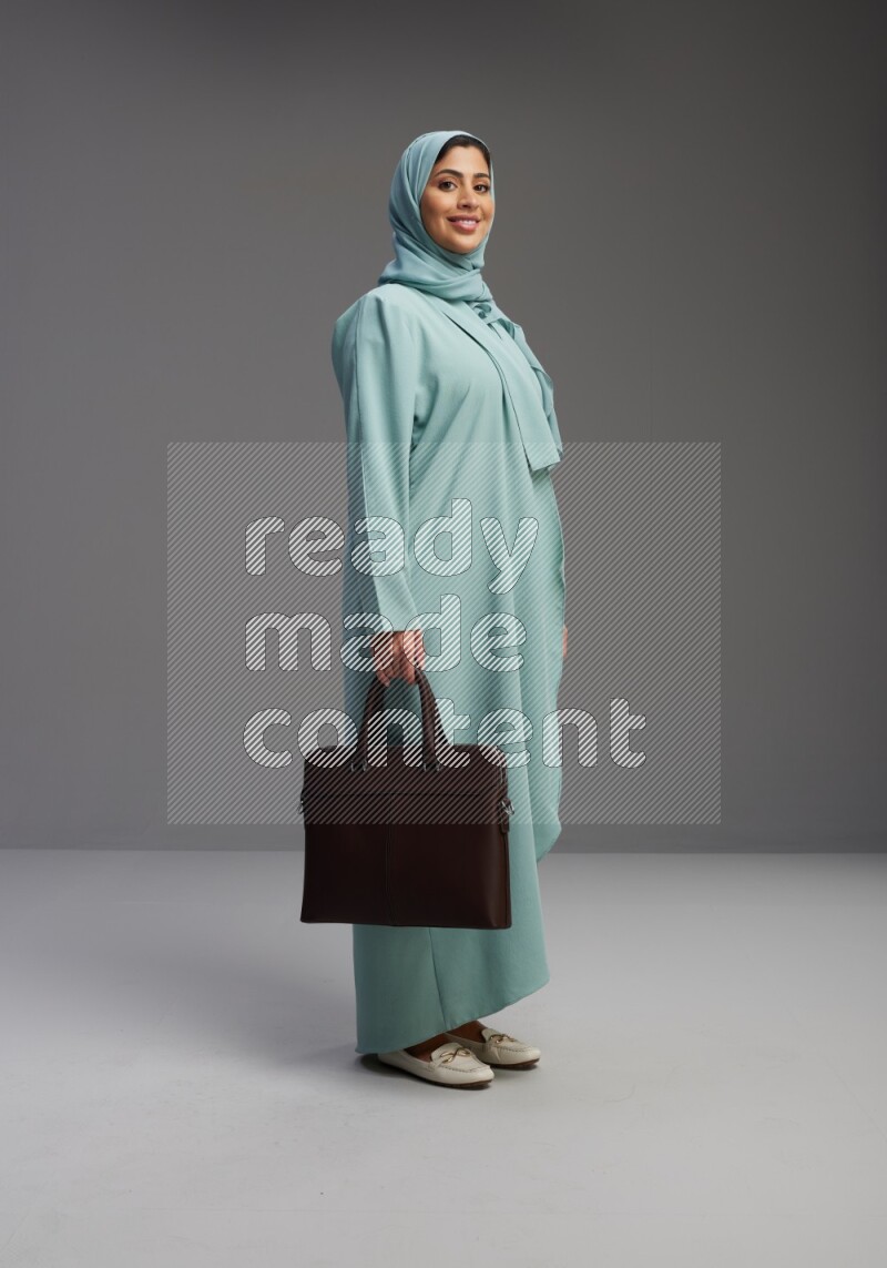 Saudi Woman wearing Abaya standing holding bag on Gray background