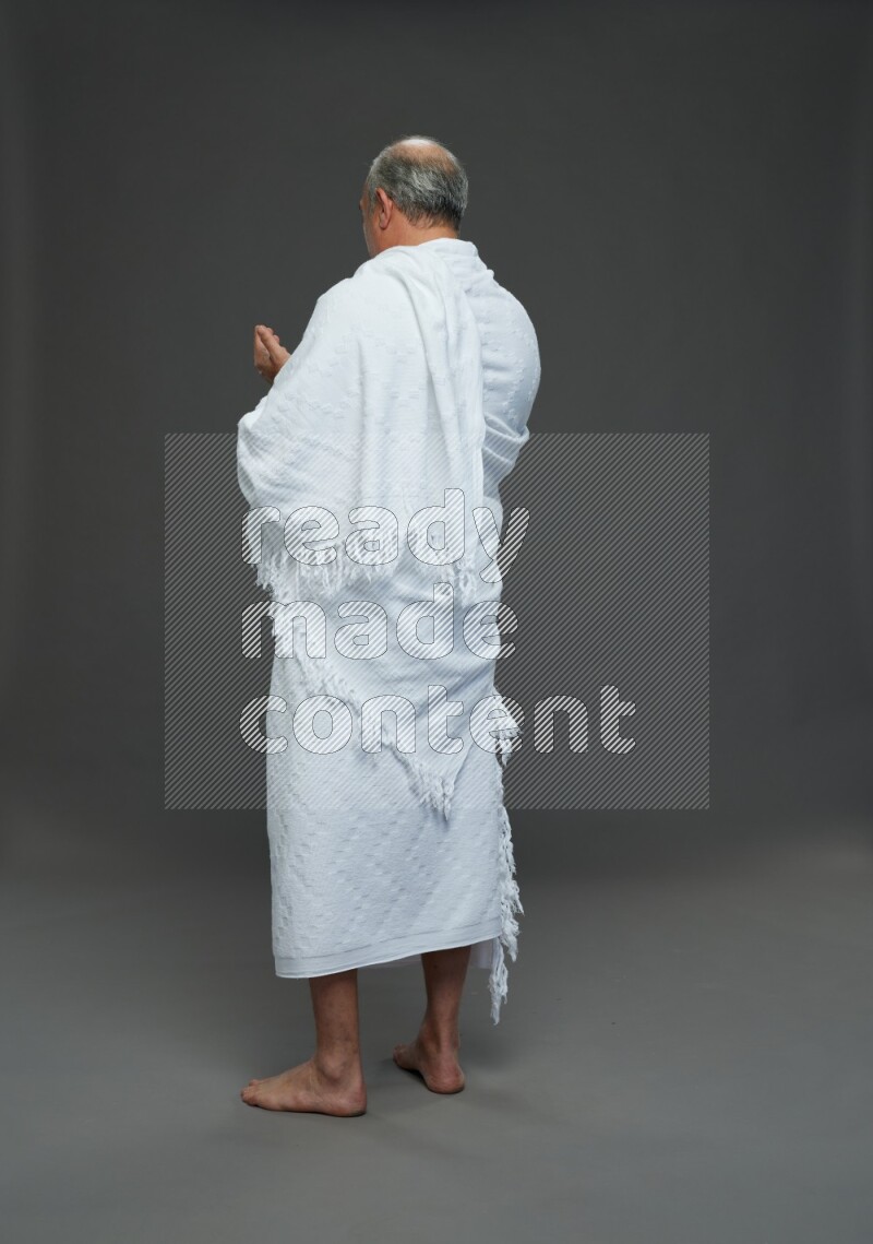 A man wearing Ehram Standing dua'a on gray background