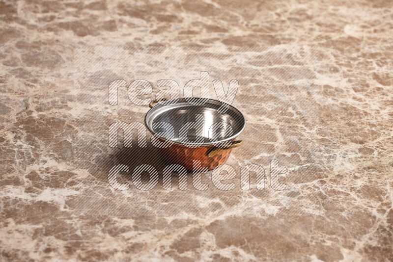 A small copper pot on beige marble background
