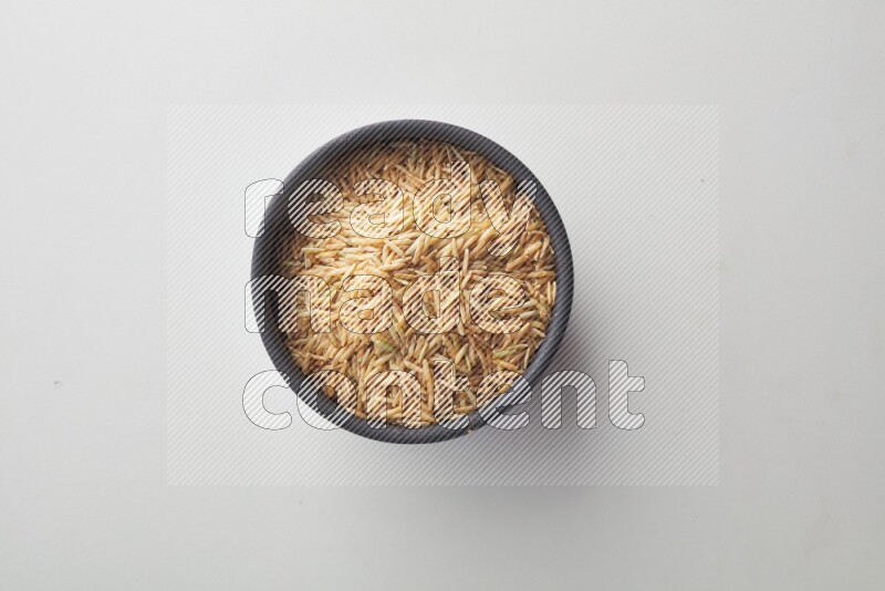 Top-view shot of long grain brown rice in a container on white background