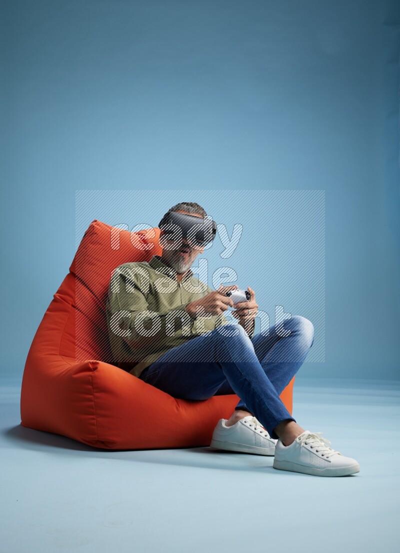 A man sitting on an orange beanbag and gaming with VR