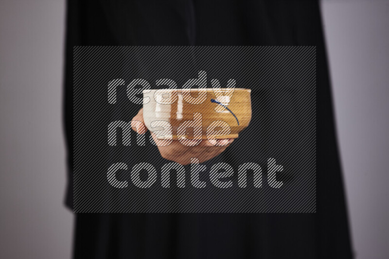 A woman in black abaya holding different pottery essentials in different positions
